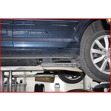 Dunkelblaues Auto auf Hebebühne, Blick auf Reifen und Unterboden. Werkstatt-Umgebung mit Hebevorrichtung.